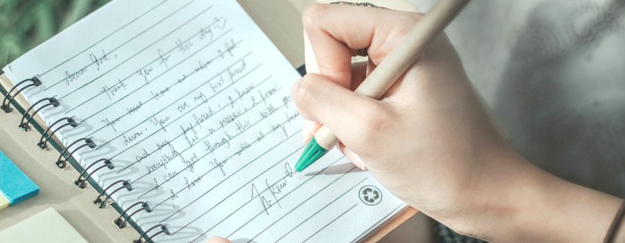 Journal Prompts For Beginners Being Written By A Woman In A Lined Notepad