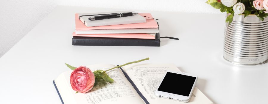 Self Love Affirmations Graphic Of A White Desk With Pink And Blue Notebooks Phone And Pink Rose