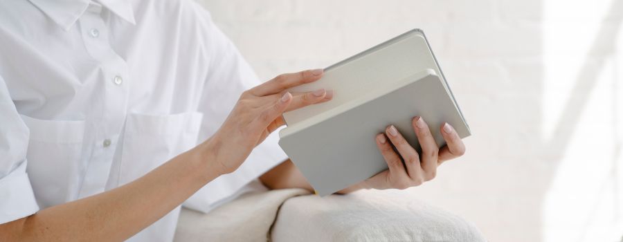 Woman In White Shirt Looking Through Positive Mindset Journal Prompts In Her Grey Notebook